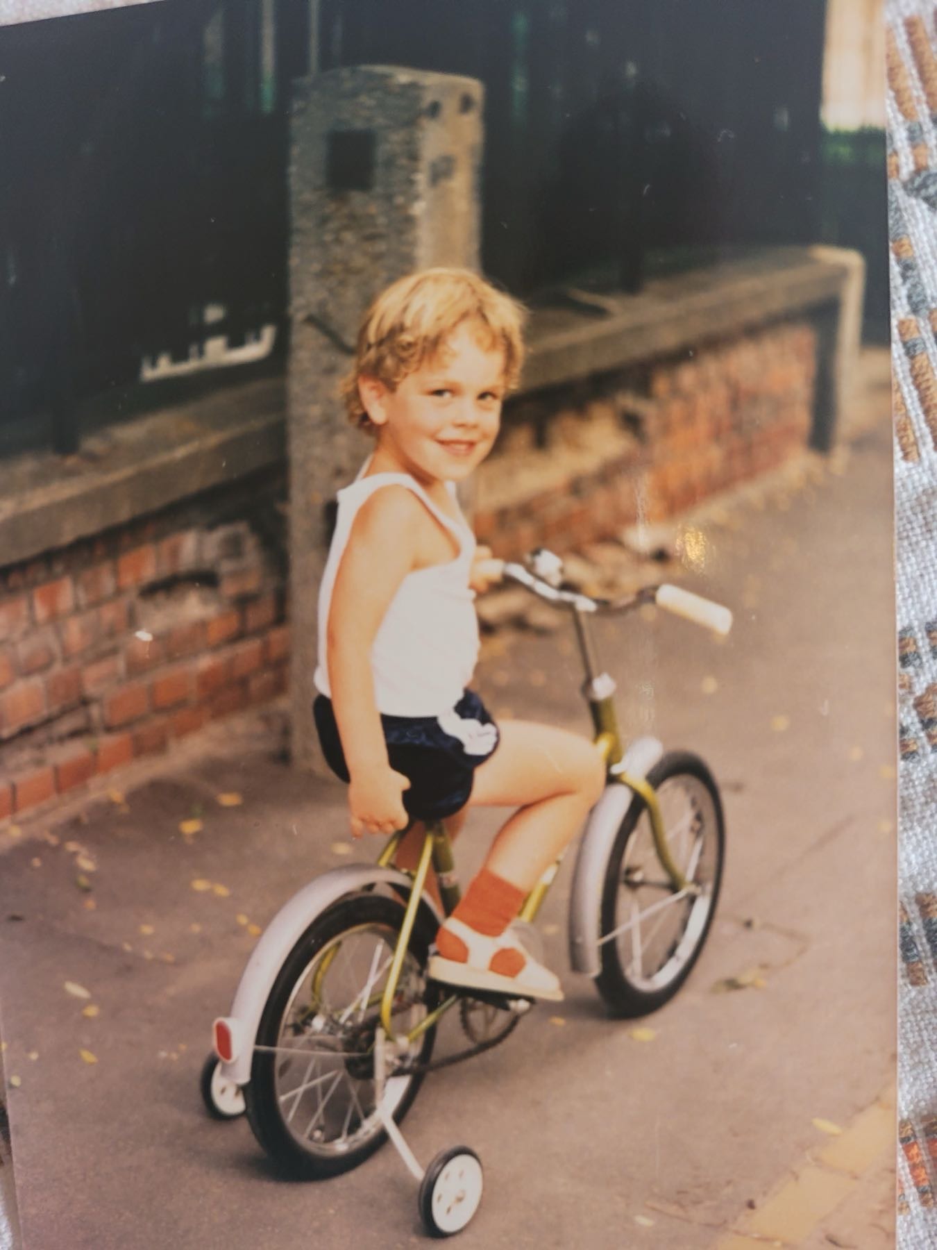 Adam de niño, con rueditas, sobre una calle empedrada de Budapest.