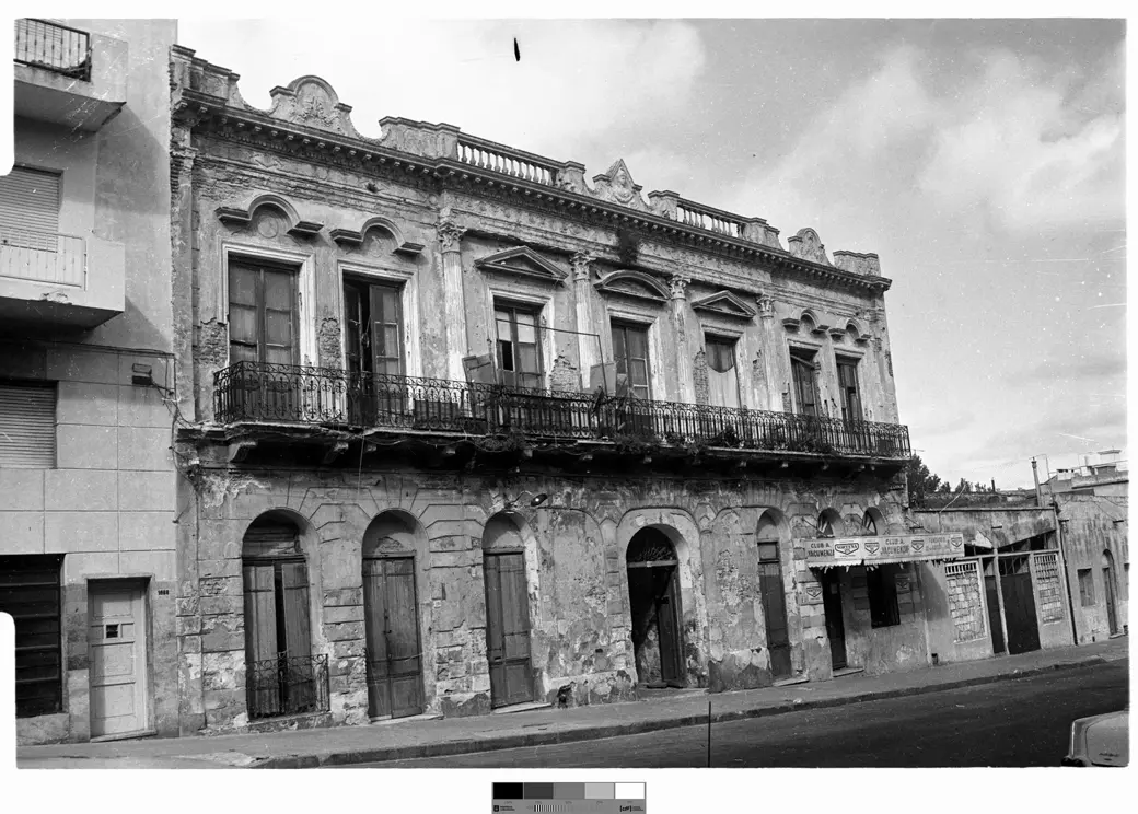 Foto histórica, catalogada hacia 1979: la fachada del conventillo Medio Mundo en Cuareim 1080, deteriorada pero en pie, con el cartel de un club sobre un local de planta baja.