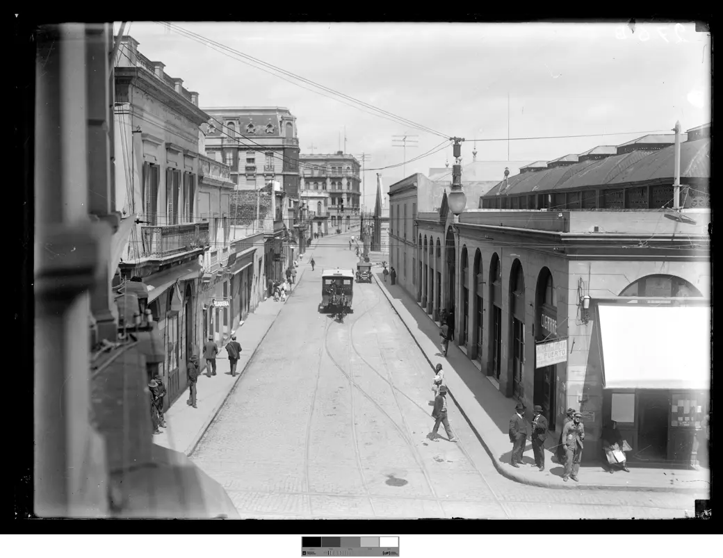 Foto histórica, hacia 1920: la calle Piedras con la fachada del Mercado del Puerto y la vía del tranvía en primer plano.