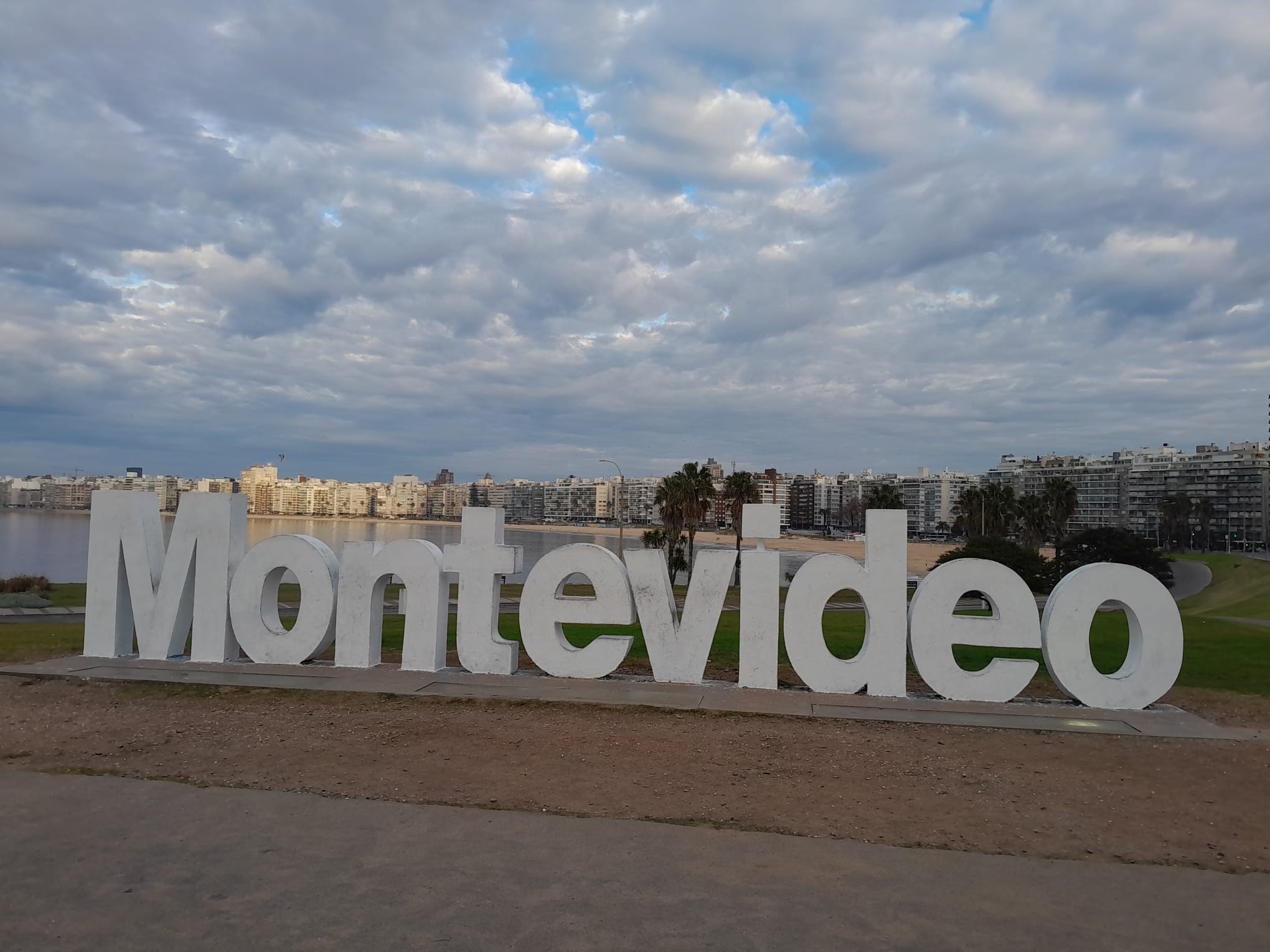 Las letras de MONTEVIDEO en la rambla de Pocitos, con la playa y las torres detrás.