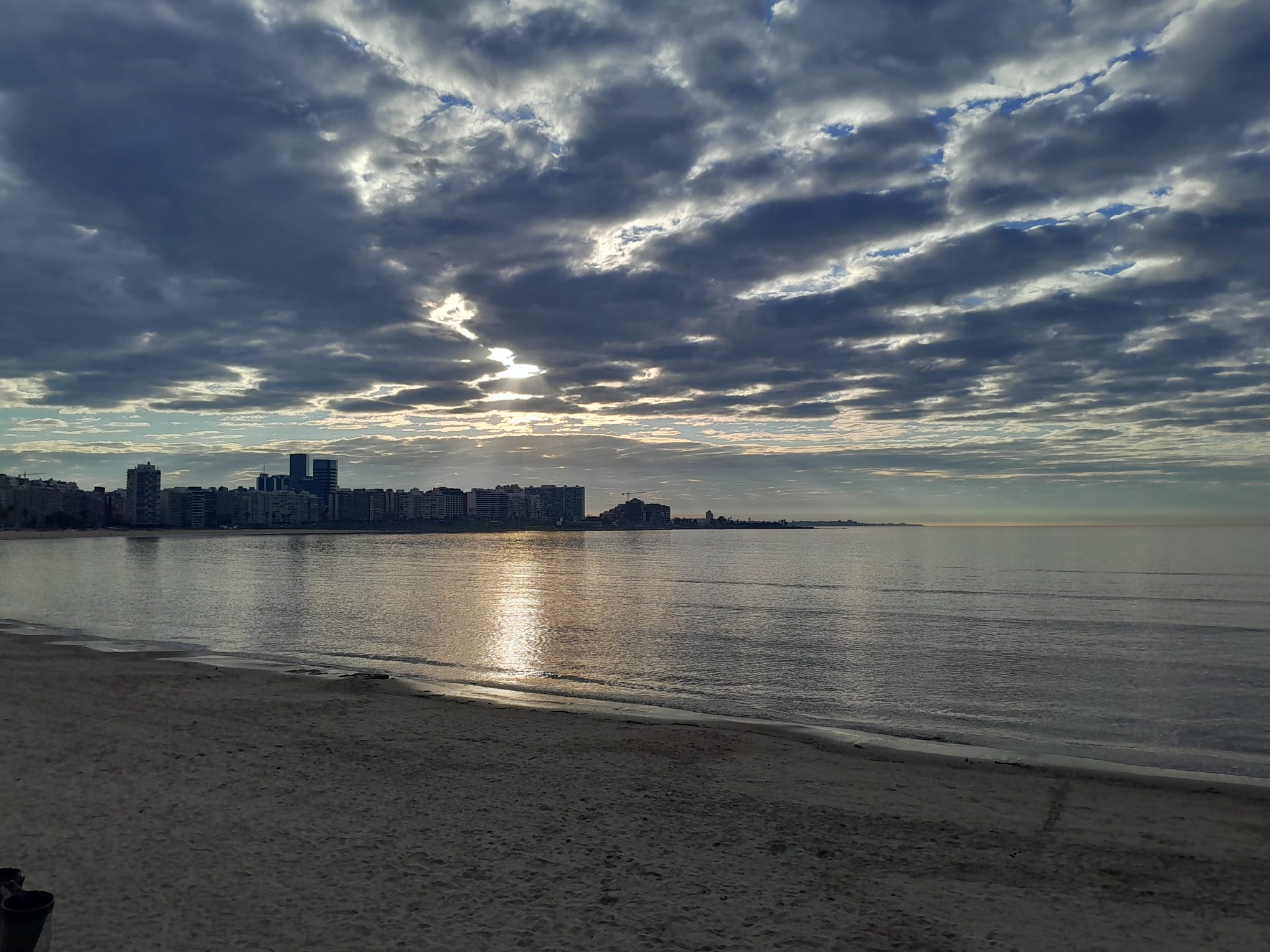 La bahía de Pocitos con sus torres, sol filtrándose entre las nubes sobre el río.