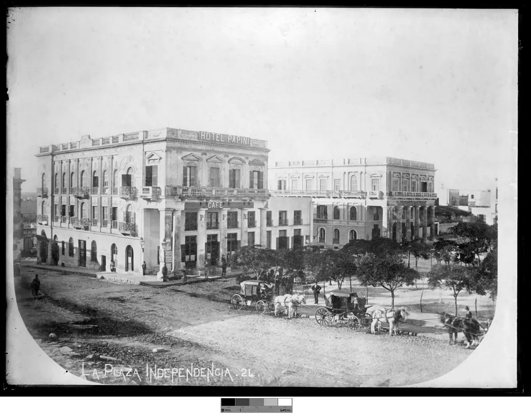 Foto histórica, hacia 1880: la Plaza Independencia sin pavimentar, con varios carruajes tirados por caballos y el Hotel Papini al fondo.