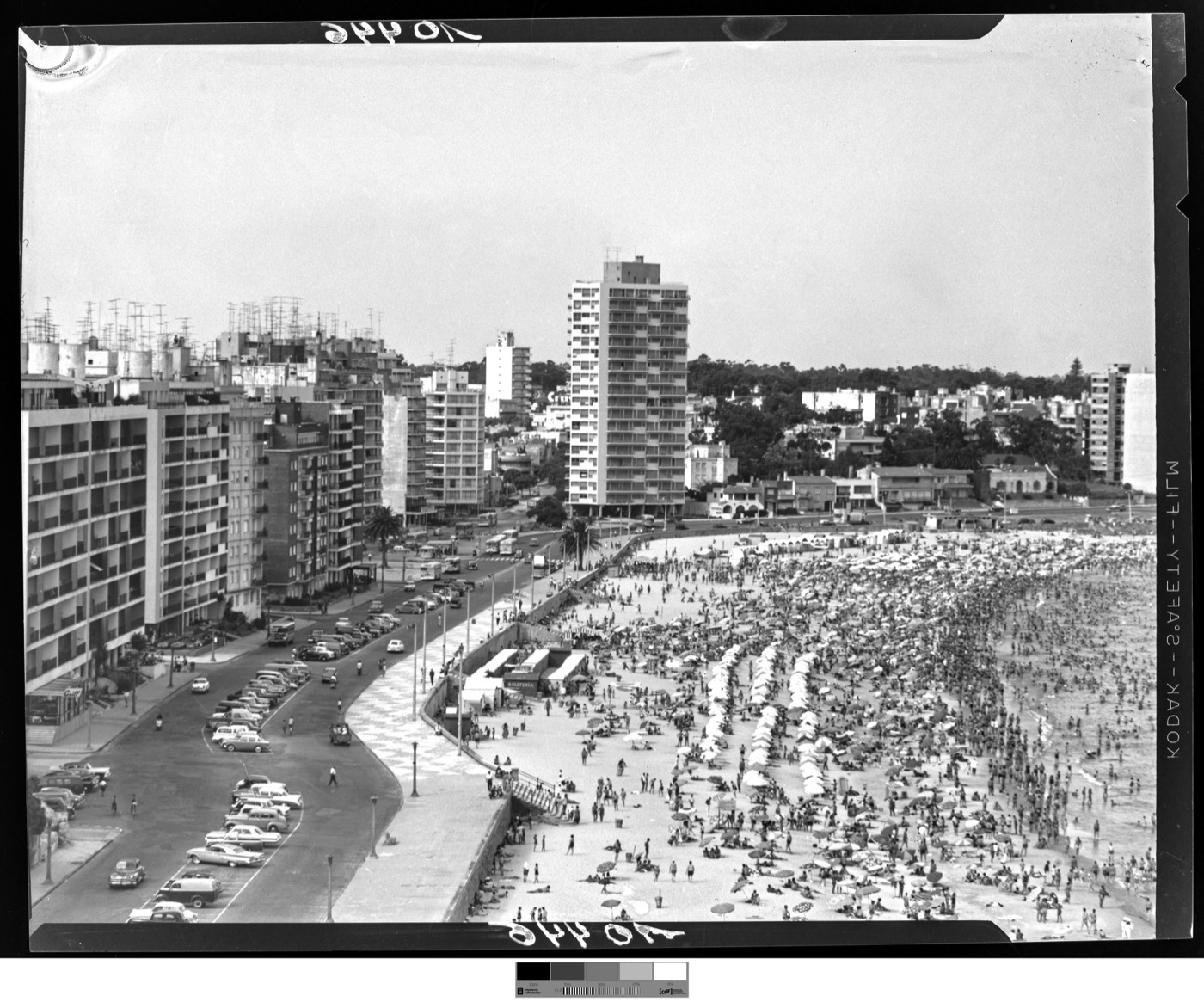 Foto histórica, enero de 1964: playa y rambla de Pocitos con la arena repleta y autos estacionados de punta a punta.